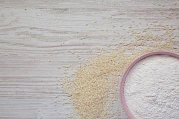Gluten free rice flour in a pink bowl over white wooden surface, top view. Copy space.