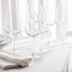 Several empty wine glasses in white grey shades on the white tablecloth
