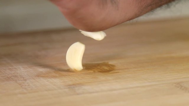 Close up shot of a man crushing cloves of garlic with hands. 
