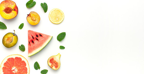 Tropical Summer Fruit Concept. Creative layout made of fresh ripe watermelon, peach, plum, fig, lemon, grapefruit and mint leaves on white background. Flat lay, top view, copy space. Food background