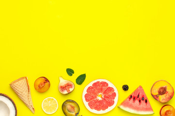 Tropical Summer Fruit Concept. Creative layout made of fresh ripe watermelon, peach, plum, fig, lemon, grapefruit, waffle ice cream cup, mint leaves on yellow background. Flat lay top view copy space