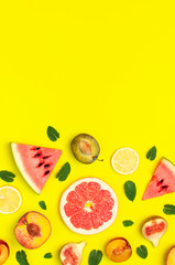 Tropical Summer Fruit Concept. Creative layout made of fresh ripe watermelon, peach, plum, fig, lemon, grapefruit and mint leaves on yellow background. Flat lay, top view, copy space. Food background