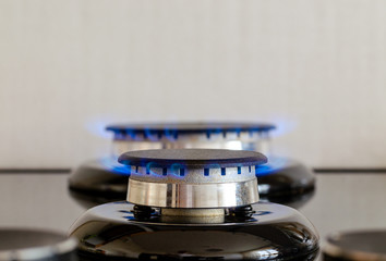 Two gas burners with a flame on a glass surface. Kitchen stove on a light background. Frontal image...