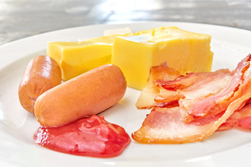 omelette breakfast ingredients isolated on white plate against wooden table background closeup crop view of eggs dish feta cheese smoked bacon hot dog sausages ketchup sauce restaurant food
