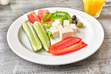 greek salad healthy food on white plate and orange juice glass on wooden table background top closeup view of fresh vegetarian ingredients feta cheese tomato olive oil cucumber mediterranean cuisine
