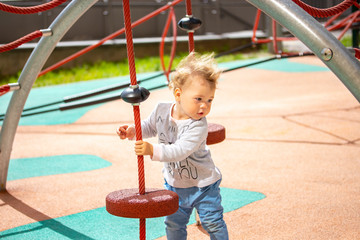 Toddler 1 year girl boy, Caucasian on the playground, fluttering blond hair