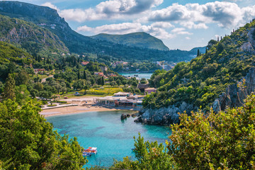Beautiful landscape with sea–lagoon, beach, mountains and cliffs, green trees and bushes, rocks in a blue water, blue sky and clouds. Corfu Island, Greece.  - obrazy, fototapety, plakaty