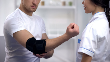 Patient checking elbow pad brace at traumatologist, sports injury, healthcare