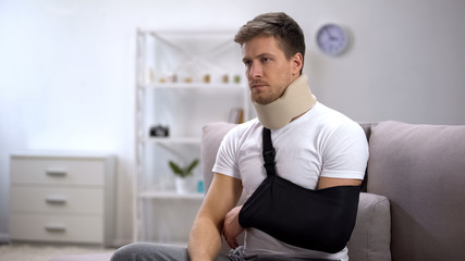Man in foam cervical collar and arm sling unhappy because of disability, rehab