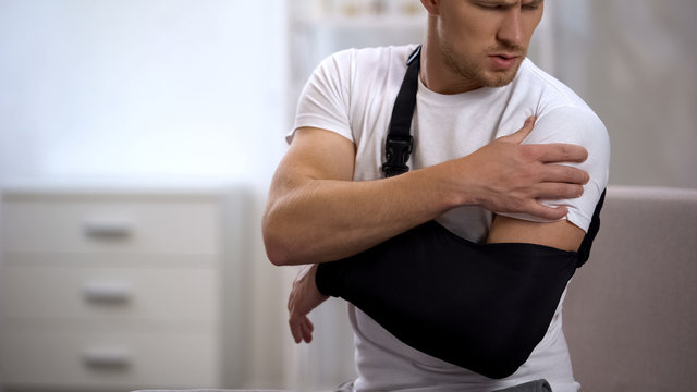 Man wearing arm sling feeling pain in shoulder, result of trauma, orthopedics
