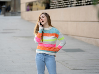 Attractive young teenager woman talking and chatting on her smart phone outside in an European city