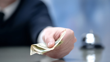 Male hand gives money at hotel reception, paying for business trip accommodation