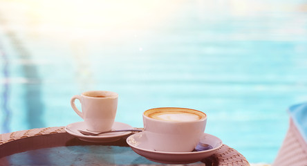 A cup of cappuccino and coffee on the background of emerald pool water.