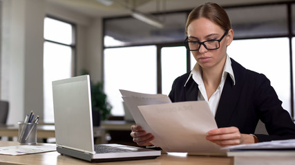 Businesswoman working with papers, checking annual financial report in office