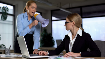 Lady boss shouting with megaphone at colleague, authoritarian leadership