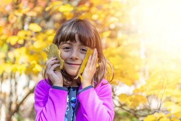 Cute young girl holding two leaves in foliage season, New England