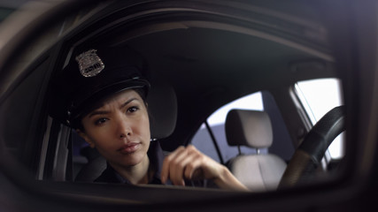 Fototapeta na wymiar Asian policewoman looking at car mirror, watching risky situation, patrolling