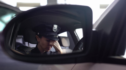 Tired police woman feeling headache, sitting in patrol car, stressed lifestyle