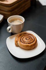 Cinnamon Roll on white dish and black coffee