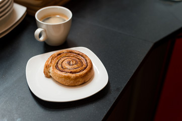 Cinnamon Roll on white dish and black coffee