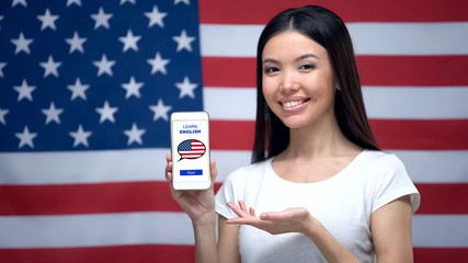Lady showing cellphone with learn English app, USA flag on background, education