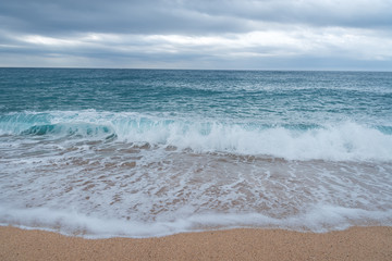 sea waves roll out on the sandy shore and break into white foam