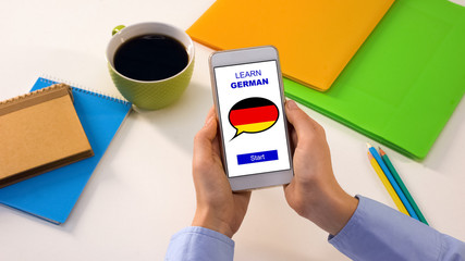 Learn German application on cellphone in persons hands, studying language online