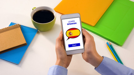 Learn Spanish application on cellphone in persons hands, studying language