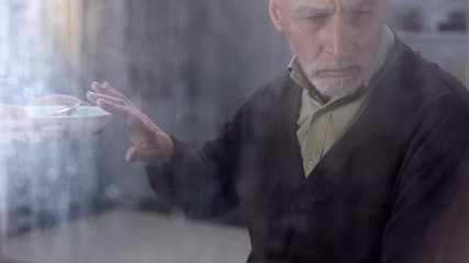 Depressed male pensioner refusing to eat porridge, feeling lonely in hospice