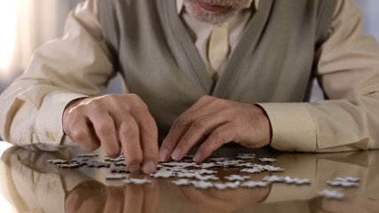 Grandfather trying to put puzzle together, concentration exercise, motor skills