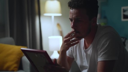 Sad man looking at photo of ex-girlfriend, and smoke