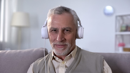 Cheerful senior male in headphones listening to music, enjoying favourite melody