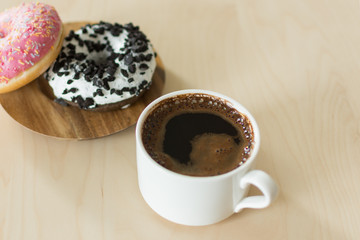 Coffee and donut for breakfast. Cup of dark espresso with sweet donut dessert.