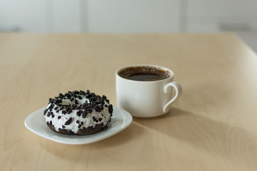 Coffee and donut for breakfast. Cup of dark espresso with sweet donut dessert.