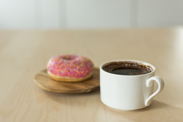 Coffee and donut for breakfast. Cup of dark espresso with sweet donut dessert.