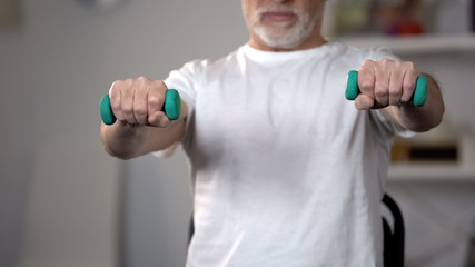 Old man lifting dumbbells, training muscles and joints after injury or insult