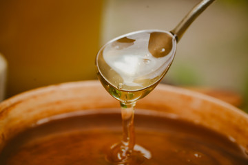 honey pour from a spoon into a clay plate