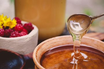 honey pour from a spoon into a clay plate