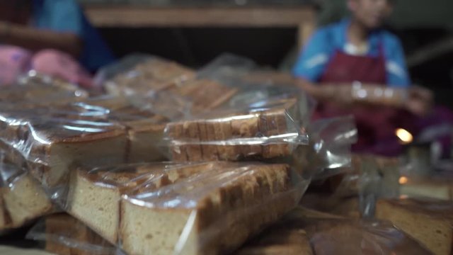 Women working in a small factory are putting a definite number of slices of bread in different packages