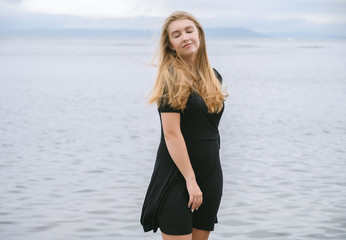 Woman in dress enjoys a walking near the sea shore.