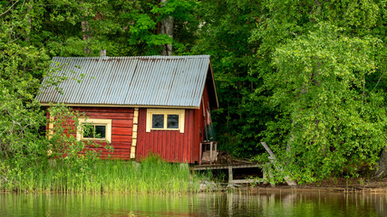 Fototapeta na wymiar An old sauna building by the lake in Finnish summer