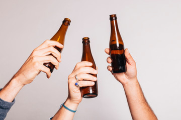 hands holding a bottle of beers and toasting up