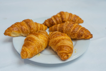 Puffy golden croissants on white plate with white background