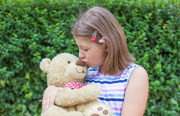 Little girl  holding large teddy bear outside