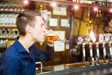 young man drinking beer while sitting in the pub