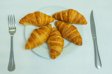 Delicious puffy croissants on white plate for breakfast in restaurant