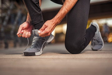 A single man tying his shoelaces, ready to start exercising for an upcoming marathon