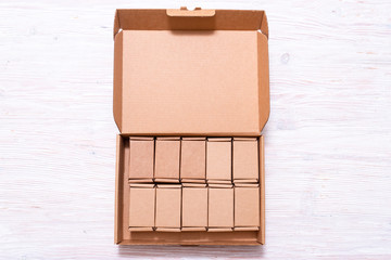 Lot of small cardboard boxes inside of large case with cover on wooden table