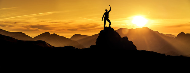 Frau in Siegerpose bei Sonnenaufgang auf einem Berggipfel