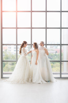 Group of beautiful brides arrange their dress..